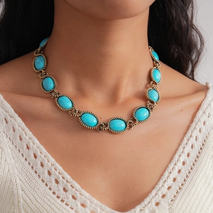 Close-up of bohemian turquoise oval stones set in vintage gold rope frames on a model