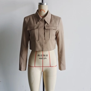 Detail of khaki short suit jacket showing textured fabric and large flap pockets