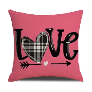 Detail van roze kussensloop met zwarte LOVE-letters en een geruit hartpatroon