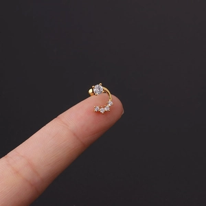 Macro shot of a tiny gold curved ear stud with micro-pave cubic zirconia on a fingertip