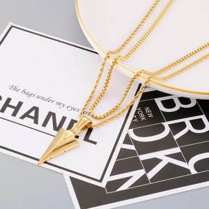 Close-up of golden double-layered necklace with arrow pendant on decorative display