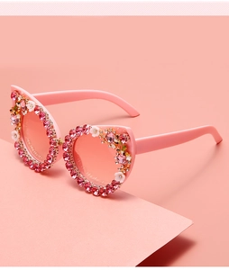 Detail of pink cat-eye sunglasses featuring delicate white flowers and sparkly rhinestones