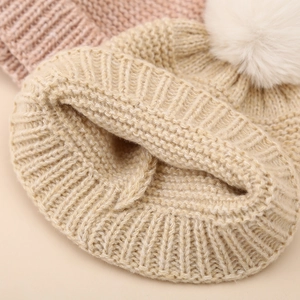 Warm beige baby knitted hat with fluffy white pom pom for autumn and winter warmth
