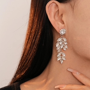 Détails rapprochés des boucles d'oreilles feuilles serties de strass brillants