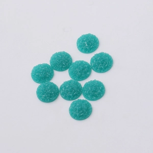 Macro detail of 12mm teal resin druzy round cabochons with sparkling matte texture