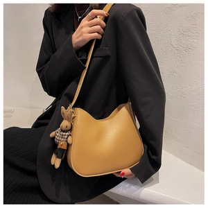 Fashionable beige leather shoulder bag with a cute rabbit plush pendant in a stylish setting