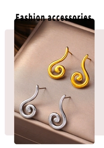 Detailed view of polished gold and silver spiral stud earrings in a silk jewelry box