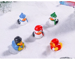 Close-up of five miniature Christmas sport ducks in snow with knit hats and helmets