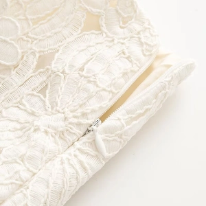 Close-up of white lace fabric texture and concealed invisible zipper detail on the skirt
