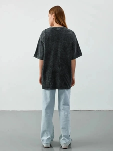 Macro detail of the acid-washed vintage grey cotton texture on an oversized t-shirt