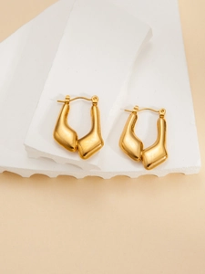 Close-up of golden U-shaped titanium steel earrings with a matte textured finish