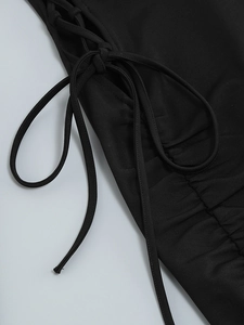 Detailed view of the side lace-up design and ruched texture on this black evening dress