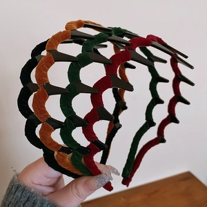 Close-up of four velvet wavy headbands in black, yellow, green, and red colors