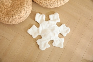 Detailed top view of white snowflake plush rug on a rustic wooden herringbone floor