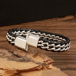 Detail of men's braided black leather bracelet with silver metal chain and magnetic clasp