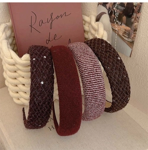 Close-up of four tweed and wool hairbands in burgundy and brown in a woven basket
