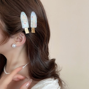 Detail of acrylic popsicle hair clips with colorful accents on a gold duckbill clip
