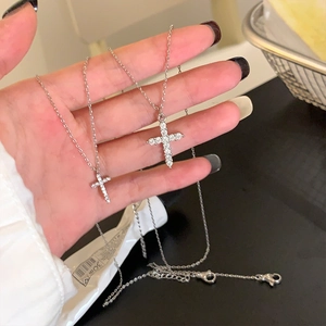 Handheld sterling silver cross necklace set with sparkling moissanite stones on chain
