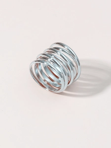 Detail shot of a layered silver spiral metal ring with a modern coil design on pink backdrop