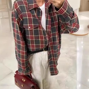 Détail d'une chemise à carreaux rouge et gris avec col classique et doubles poches avant