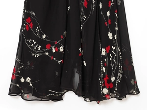 Détail d'une robe en mousseline noire avec d'élégants imprimés floraux rouges et blancs