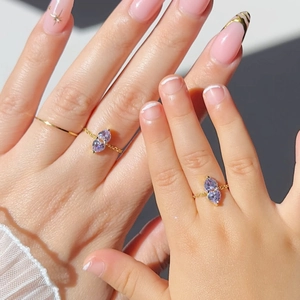 Close-up of gold adjustable pull-chain ring with two purple heart-shaped zircons on hand