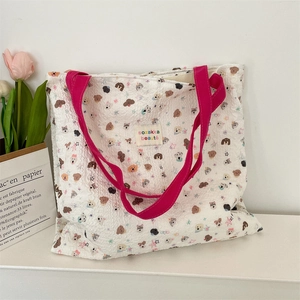 Detailed close-up of quilted canvas tote with cartoon dog prints and rose red handles