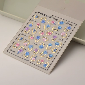 Detail of 3D embossed nail stickers featuring blue roses with golden metallic outlines