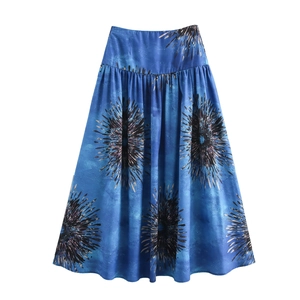 Detail of blue high-waisted maxi skirt with gold floral print on a white background