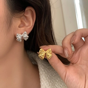 Elegant bow stud earrings in silver and gold metal finishes with a 3D folded design