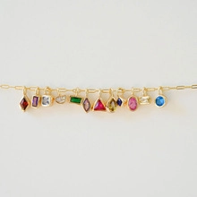 Detail of Italian charm bracelet with colorful geometric pendants on a golden chain