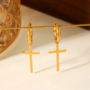 Close-up of golden stainless steel cross dangle earrings hanging on a chain link