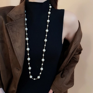 Detail of long station pearl necklace with multi-size white pearls on a gold chain