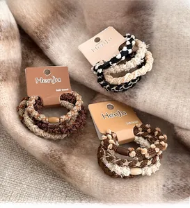 Detailed view of earth-toned knit hair ties set with plush textures on a beige fabric
