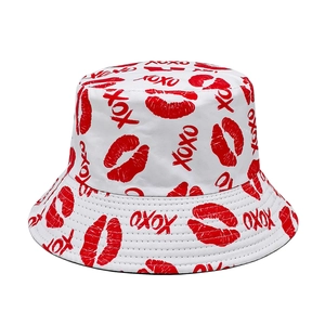 Close-up of white canvas bucket hat featuring red lip prints and XOXO pattern details