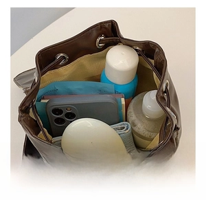 Interior view of dark brown leather bucket bag showing capacity for phone and cosmetics