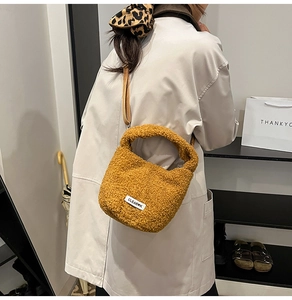 Détail d'un sac seau en polaire moutarde avec étiquette de marque et bandoulière en cuir