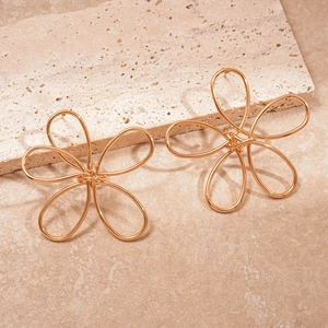 Detail view of gold petal earrings with twisted hollow design on beige stone