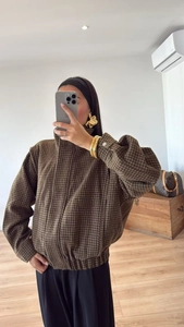 Detail einer braunen Houndstooth-Jacke mit Stehkragen und Reißverschluss für Damen