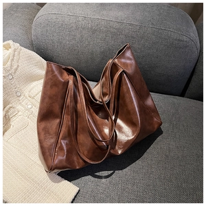 Detailed close-up of brown faux leather tote bag showing soft texture on a grey sofa