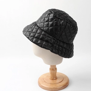 Detailed view of black quilted bucket hat with diamond lattice stitching on display stand
