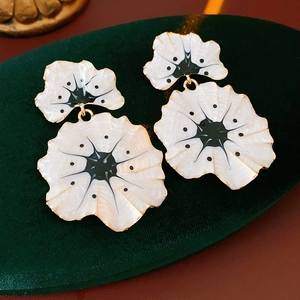 Détail de boucles d'oreilles ginkgo vintage avec émail blanc et bordure dorée sur velours