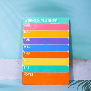Acrylic weekly planner board with colorful daily sections and notes on beach background