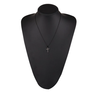 Close-up of a minimalist black cross pendant necklace on a jewelry display bust