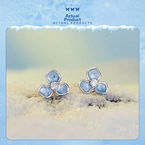 Macro shot of blue flower stud earrings with zircon center on snow background