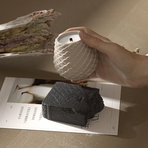 Bougie artisanale en céramique beige avec texture à écailles et mèche en bois naturel