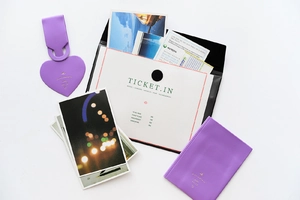 Flat lay of purple faux leather travel set including heart luggage tag and passport holder