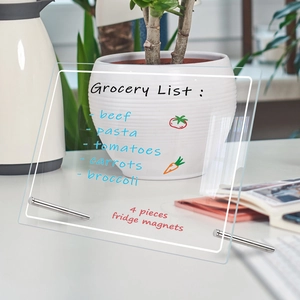 Macro view of clear acrylic weekly planner board with colorful magnets and grocery list