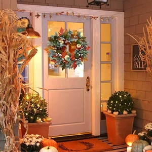 Autumn wreath with white pumpkins and maple leaves on a white front door for fall decor