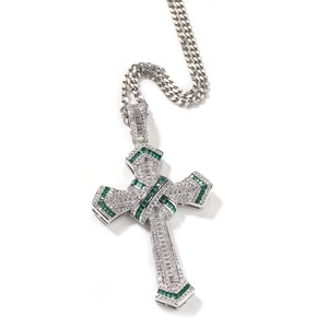 Macro detail of silver cross pendant with emerald green and clear zircon stones on Cuban chain